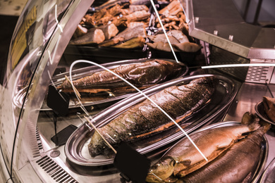Photo of Showcase with different smoked fish in supermarket