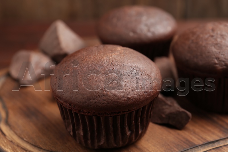 Photo of Delicious chocolate cupcakes on wooden board, closeup