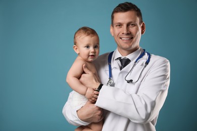 Photo of Pediatrician with cute little baby on light blue background