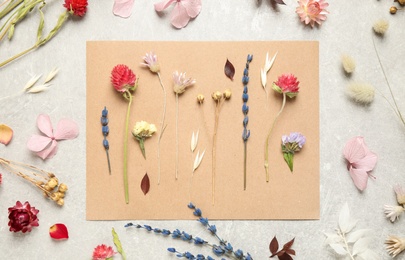 Flat lay composition with beautiful fresh and dry flowers on light grey background