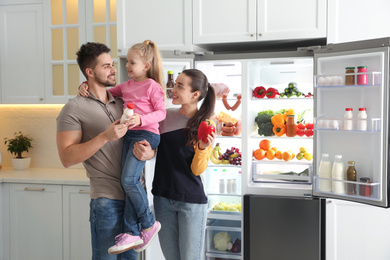 happy family with products near open refrigerator in kitchen