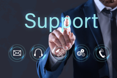 Man pointing at icon on virtual screen against dark background, closeup. Technical support service
