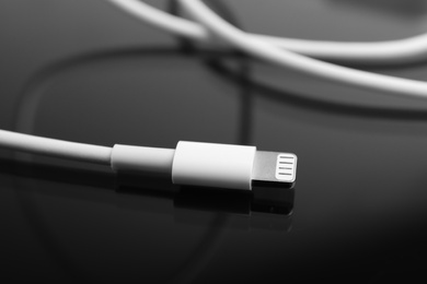 Charge cable on black reflective surface, closeup. Modern technology