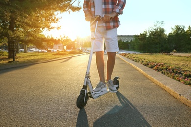 Man riding modern kick scooter in park, closeup
