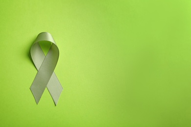 Green ribbon on color background, top view. Cancer awareness