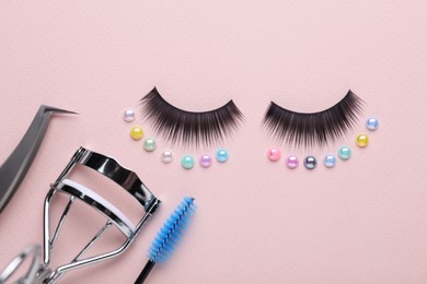 Flat lay composition with false eyelashes and cosmetic tools on pink background
