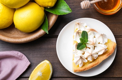 Piece of delicious lemon meringue pie with mint on wooden table, flat lay