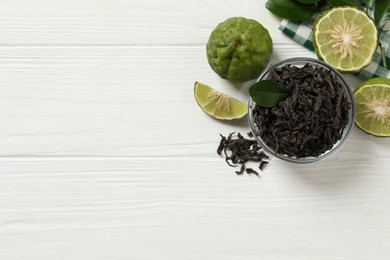 Dry bergamot tea leaves and fresh fruits on white wooden table, flat lay. Space for text