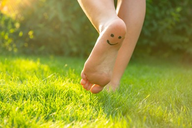 Teenage girl with smiling face drawn on heel walking outdoors, closeup