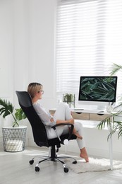 Woman resting on chair near workplace in room. Interior design
