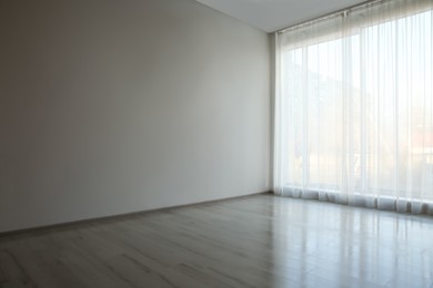 Empty room with white wall, large window and wooden floor