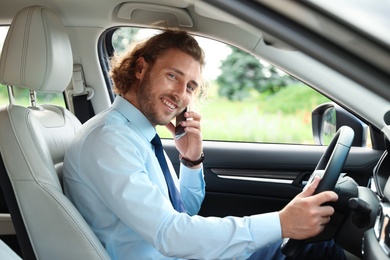 Attractive young man talking on phone while driving car