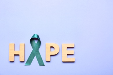 Word Hope made of wooden letters and teal awareness ribbon on lilac background, top view. Symbol of social and medical issues
