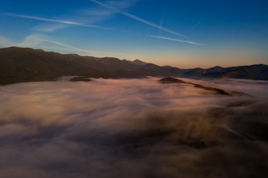 Aerial view of beautiful mountains covered with fluffy clouds. Drone photography