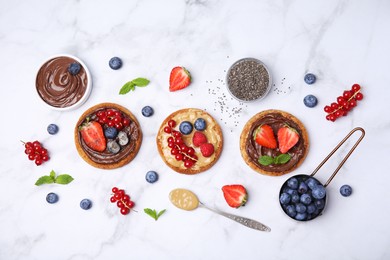 Photo of Tasty organic rusks with different toppings and ingredients on white marble table, flat lay