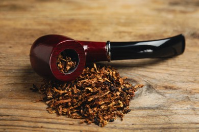 Smoking pipe with tobacco on wooden table