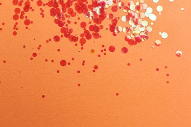 Photo of Shiny bright red glitter on pale coral background, flat lay. Space for text