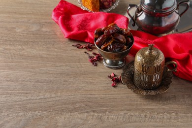 Photo of Tea and date fruits served in vintage tea set on wooden table, space for text