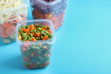 Set of plastic containers with fresh food on light blue background, space for text