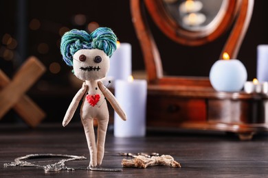Female voodoo doll with pins in heart and ceremonial items on wooden table, space for text