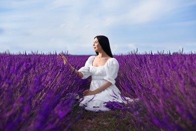 Beautiful young woman sitting in lavender field