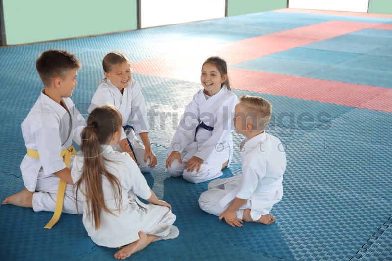 Group of children in kimono sitting on tatami after karate practice