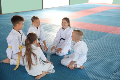 Group of children in kimono sitting on tatami after karate practice