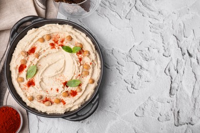 Delicious hummus with chickpeas and paprika served on white textured table, flat lay. Space for text