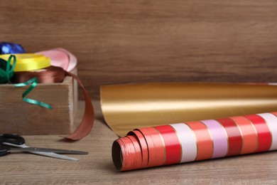 Roll of wrapping paper, scissors and ribbons on wooden table