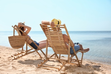 Young couple relaxing in deck chairs on beach