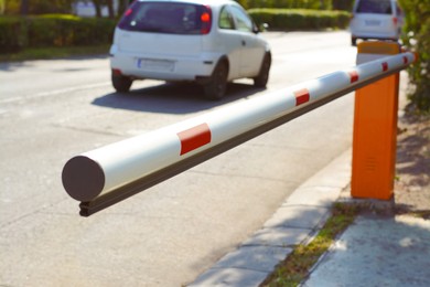 Photo of Closed boom barrier near road on sunny day, closeup