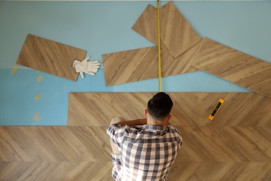 Professional worker installing new parquet flooring indoors, top view