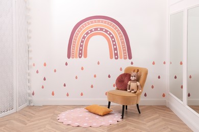 Child's room interior with comfortable armchair, toy and painting on white wall. Stylish design