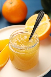 Delicious orange marmalade in jar on plate
