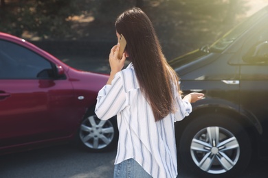 Young woman talking on phone after car accident outdoors, back view