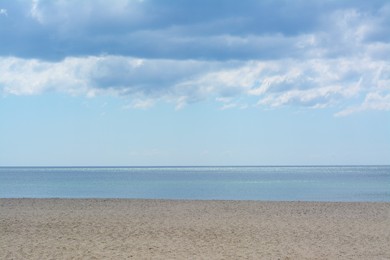 Photo of Picturesque view of sandy beach near calm sea on cloudy day