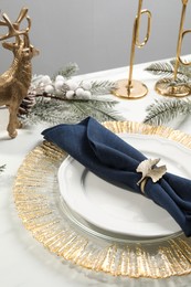 Stylish table setting with dark blue fabric napkin, beautiful decorative ring and festive decor, closeup