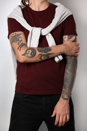 Young man with stylish tattoos on white background