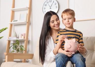 Photo of Mother and his son with ceramic piggy bank indoors
