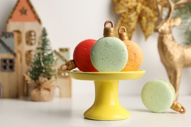 Stand with beautifully decorated Christmas macarons on white table