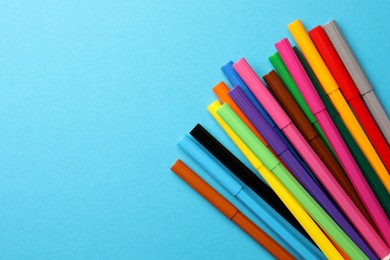 Photo of Many bright markers on light blue background, flat lay. Space for text