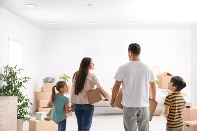 Family in room with cardboard boxes on moving day
