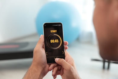 Man using fitness app on smartphone indoors, closeup