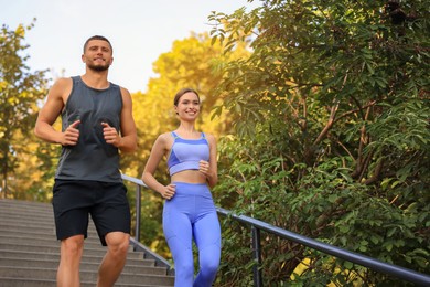 Photo of Attractive sporty couple running down stairs outdoors on sunny day