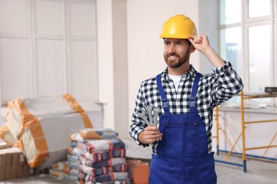 Professional builder in uniform with tools indoors