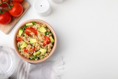 Delicious quinoa salad with tomatoes, avocado and parsley served on white table, flat lay. Space for text