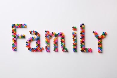 Photo of Word Family made of melty beads on white background, flat lay