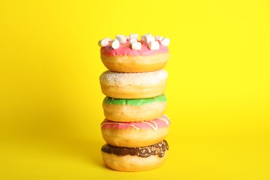Stacked sweet tasty glazed donuts on yellow background
