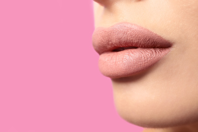 Woman with matte lipstick on pink background, closeup. Space for text