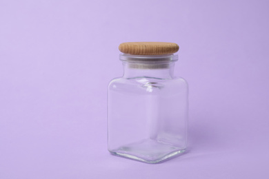 Closed empty glass jar on lilac background